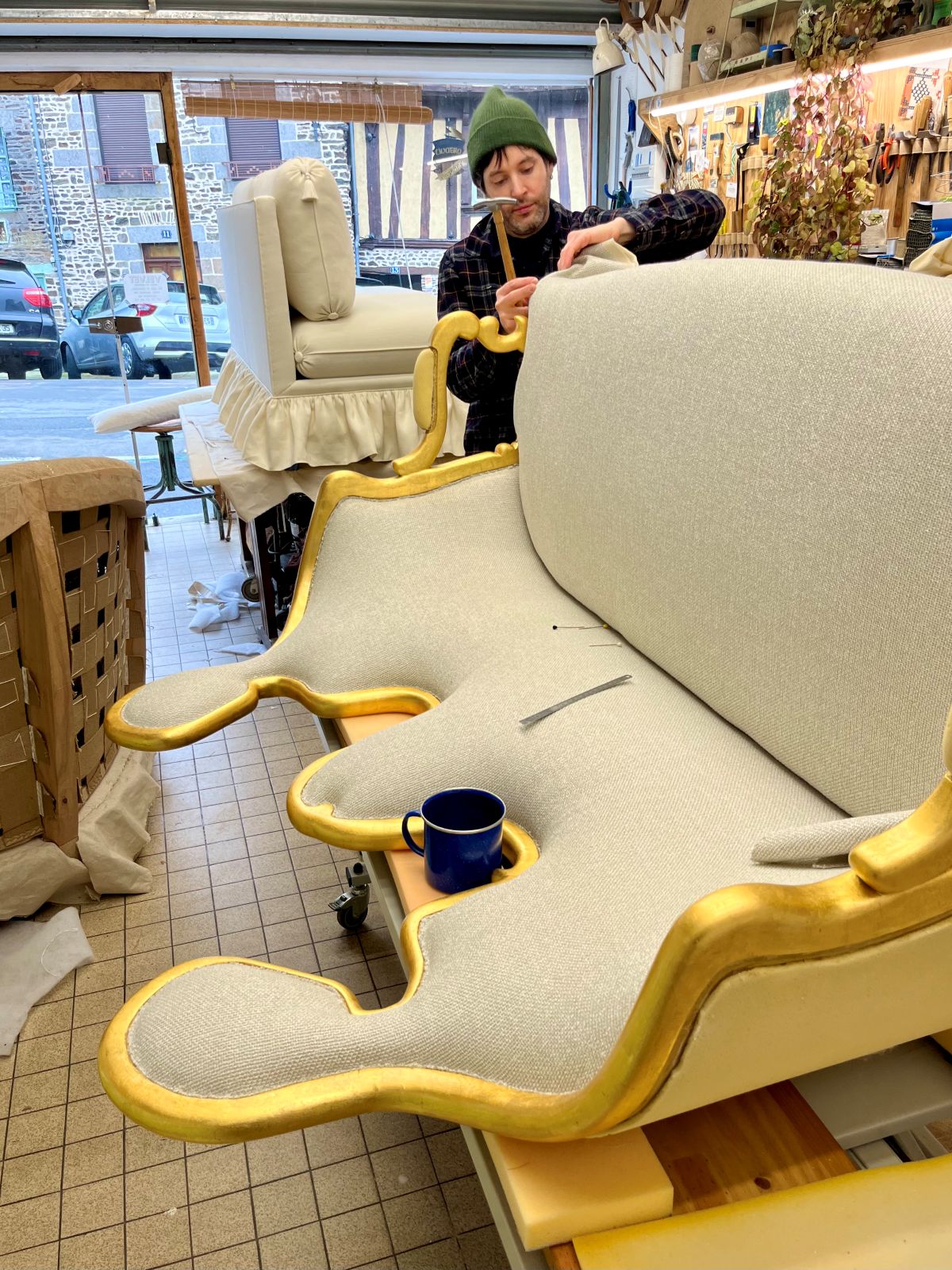 Julien Barbier façonnant à la main le dossier capitonné d'un canapé, dans l'atelier Velvet à Fougères